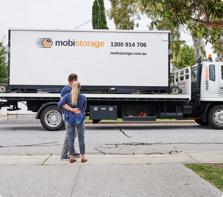 man and women observing mobile storage container on truck