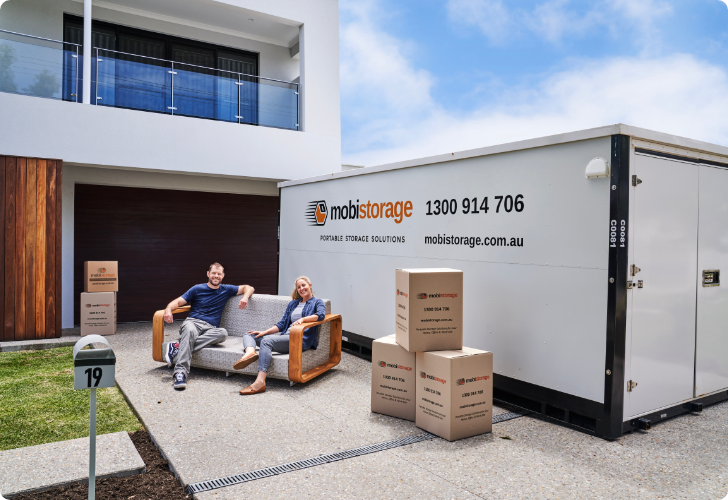 A couple sitting on their couch beside a mobistorage container
